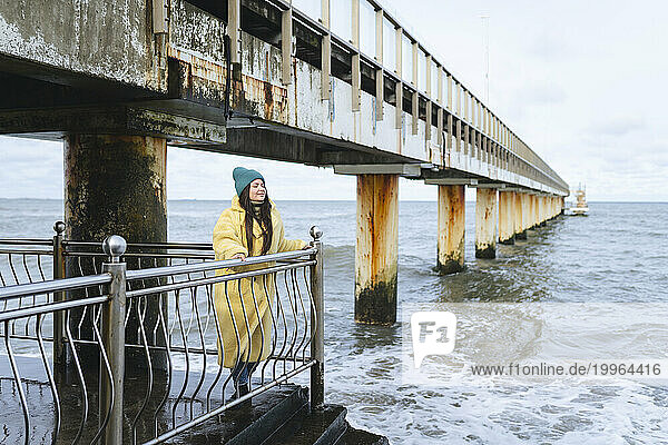 Carefree woman standing near railing at sea