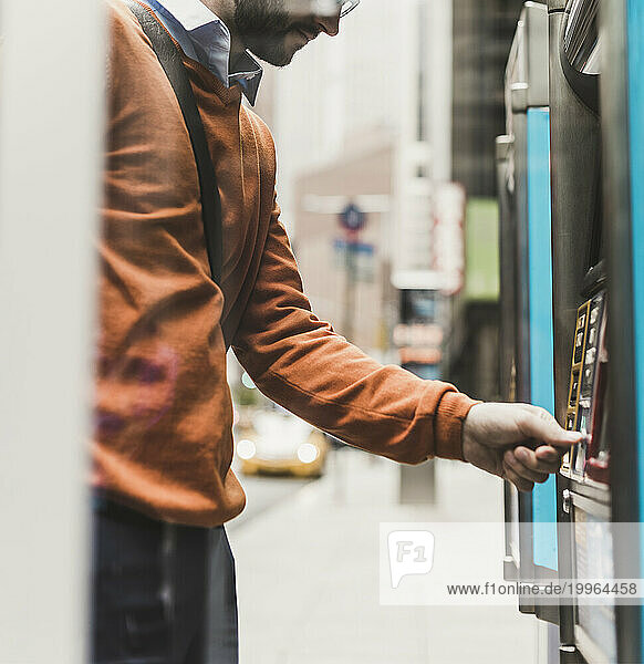 Young businessman using ATM machine
