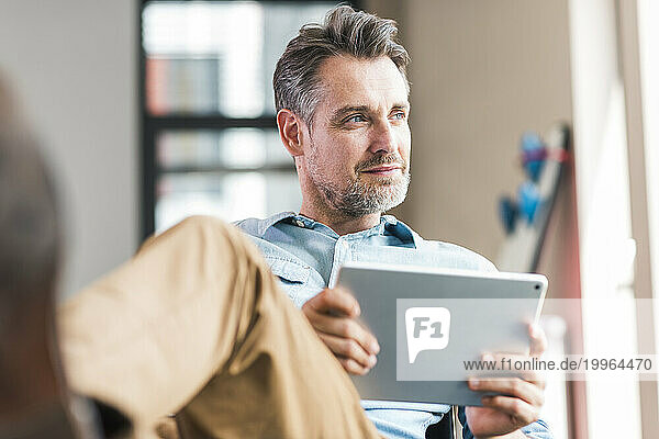 Businessman sitting with tablet PC in hand