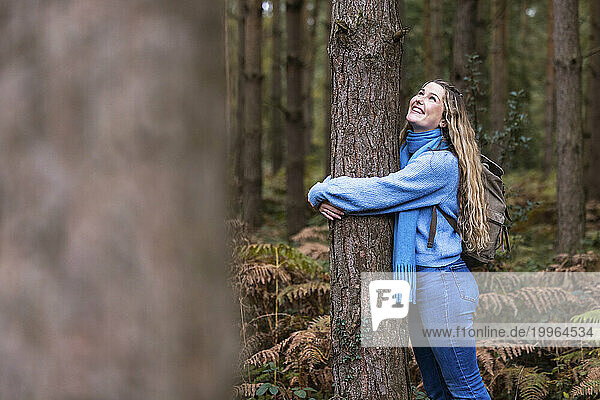 Smiling beautiful woman hugging tree in Cannock chase forest