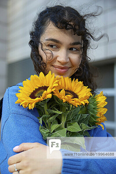 Happy woman holding bunch of sunflowers