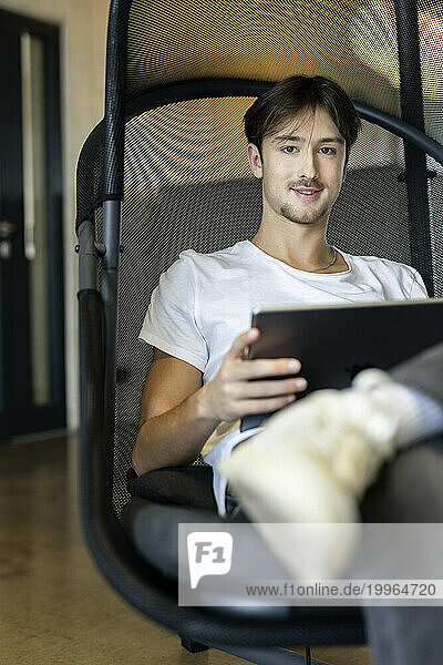 Young businessman with tablet computer sitting on chair