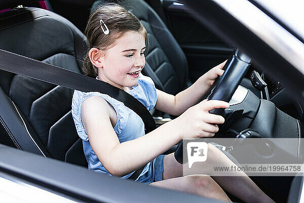 Excited girl holding steering wheel sitting in car