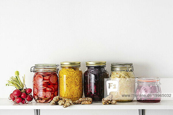 Homemade pickled vegetables in jars on shelf at home