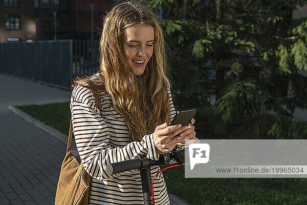 Smiling blond woman text messaging on smart phone