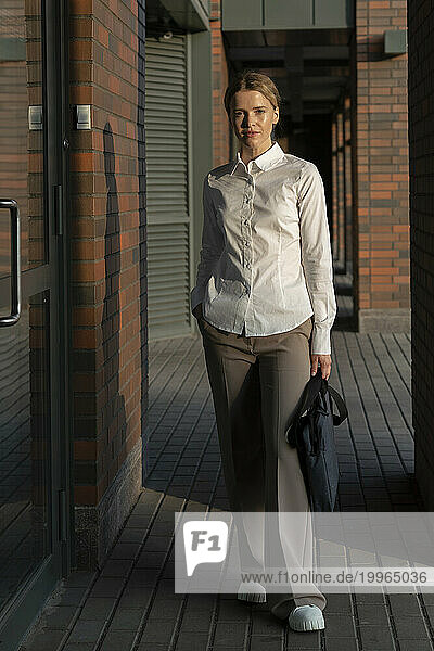 Confident businesswoman with bag standing on footpath