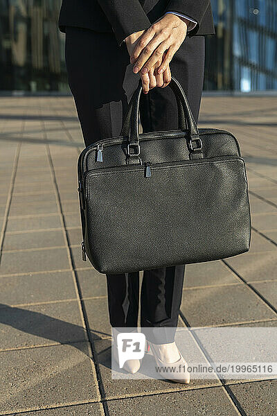 Businesswoman standing with briefcase standing on pavement