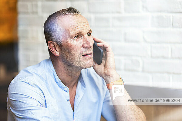 Businessman talking on smart phone at cafe