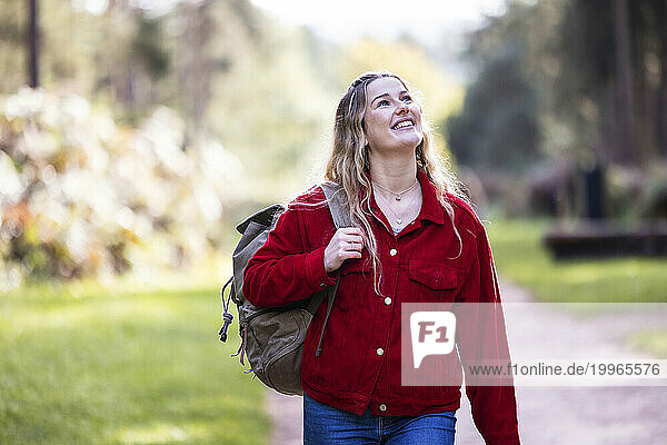 Happy young woman walking with backpack on footpath in Cannock chase forest