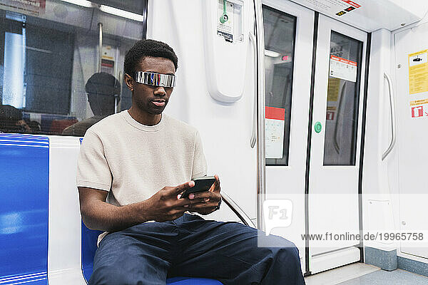 man with cyber glasses using smartphone sitting in metro