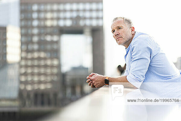 Thoughtful mature businessman standing on bridge