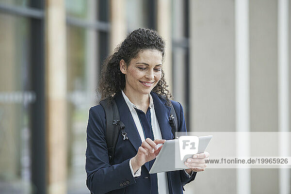 Smiling curly haired businesswoman using tablet PC