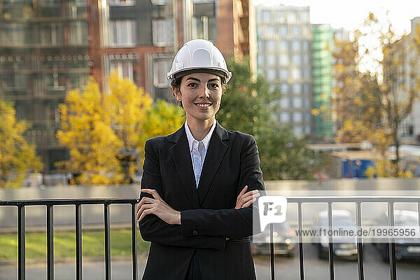 Smiling engineer standing in front of railing in city