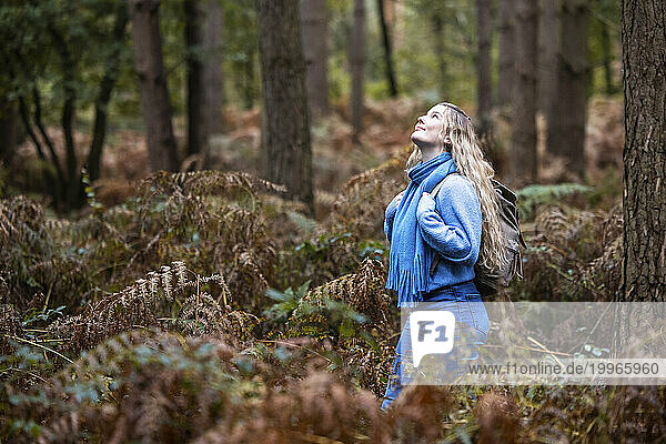 Smiling young woman with backpack in Cannock chase forest