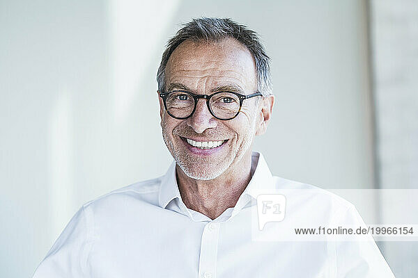 Happy senior businessman in front of white wall