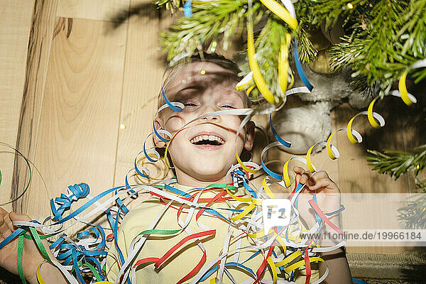 Cheerful boy lying with party poppers at home
