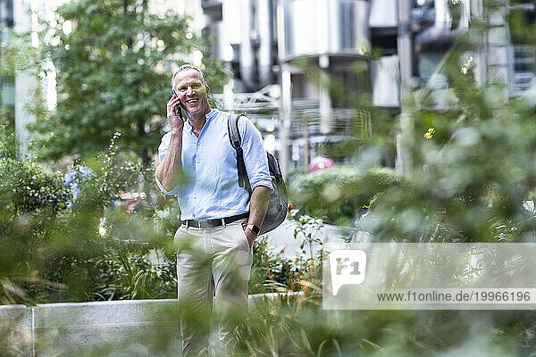 Happy businessman talking on smart phone at office park