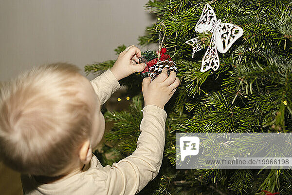 Boy decorating Christmas tree at home