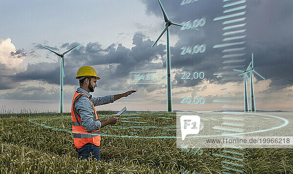 Engineer wearing hardhat and programming digital wind turbine through tablet PC in field