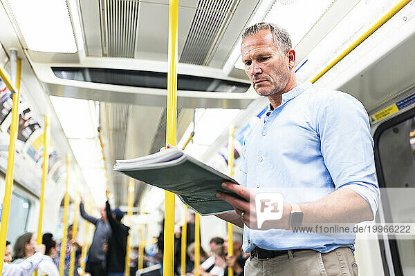 Mature businessman reading newspaper on train