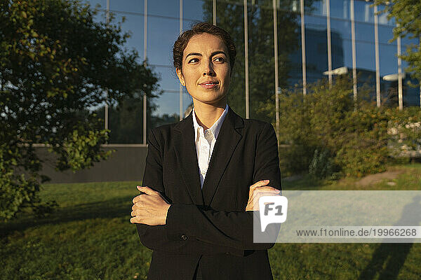 Thoughtful businesswoman with arms crossed in office park