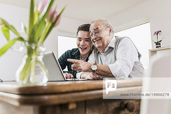 Happy senior man and grandson talking on video call through laptop