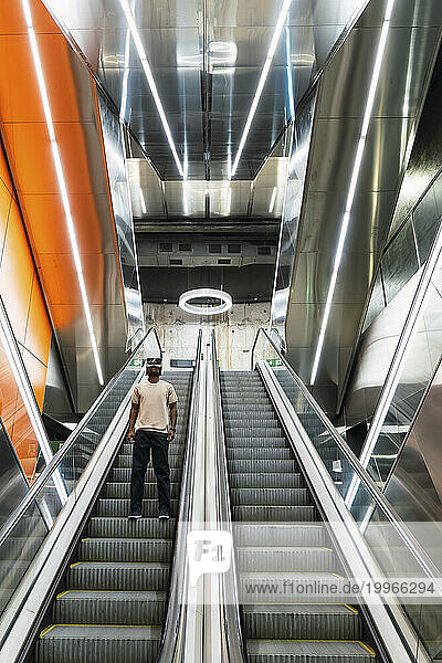 Young man standing on escalator at metro station