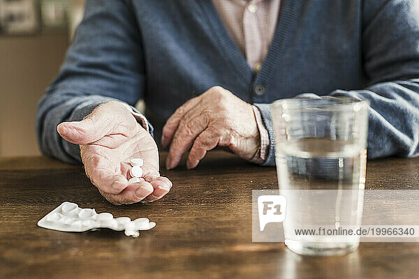 Senior man taking medicines at home