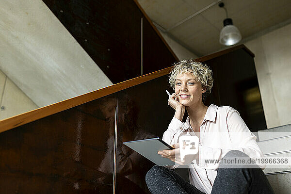 Businesswoman with tablet computer sitting on steps