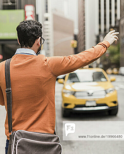 Businessman standing on street and hailing taxi