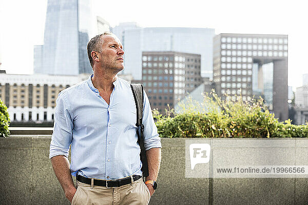 Mature businessman standing with hands in pockets at London  UK