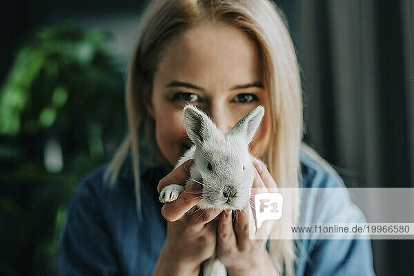 Woman holding bunny in front of face at home
