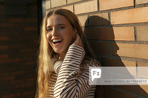 Happy blond woman in front of brick wall