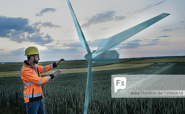 Maintenance engineer working near digital wind turbine in field