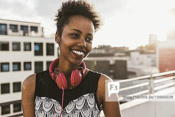 Smiling woman with headphones on rooftop