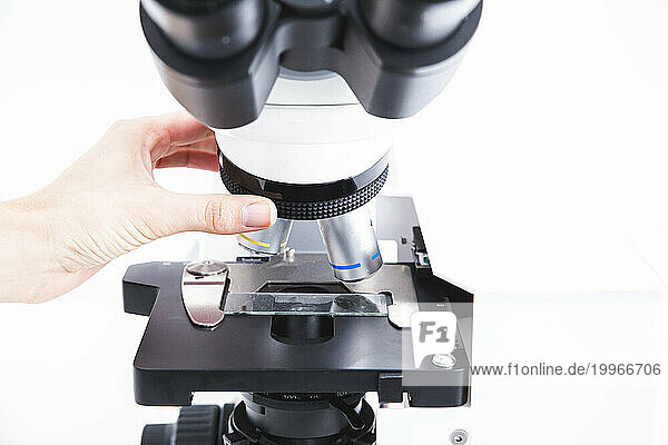Hand of scientist adjusting microscope at laboratory