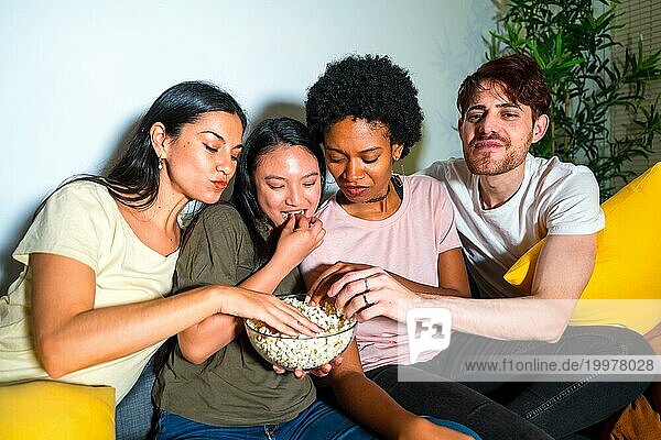 Freunde genießen Popcorn bei einem Filmabend auf dem Sofa zu Hause