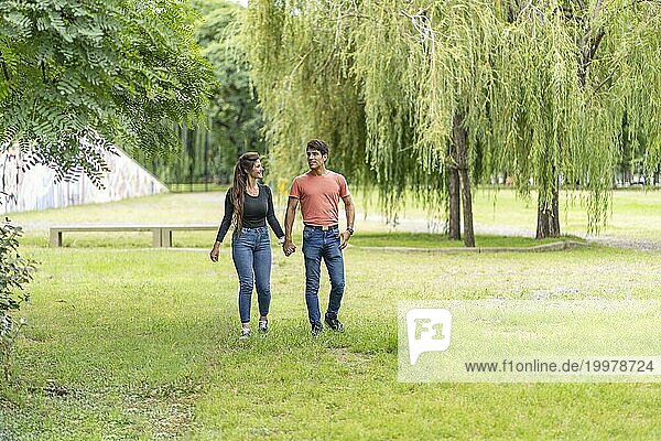 Verliebtes Paar spaziert händchenhaltend im Park