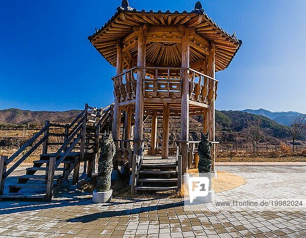 Zwei Bronzestatuen von Drachen stehen vor einem zweistöckigen Holzpavillon in einem öffentlichen Park in der Nähe von Geumsan  Südkorea  Asien