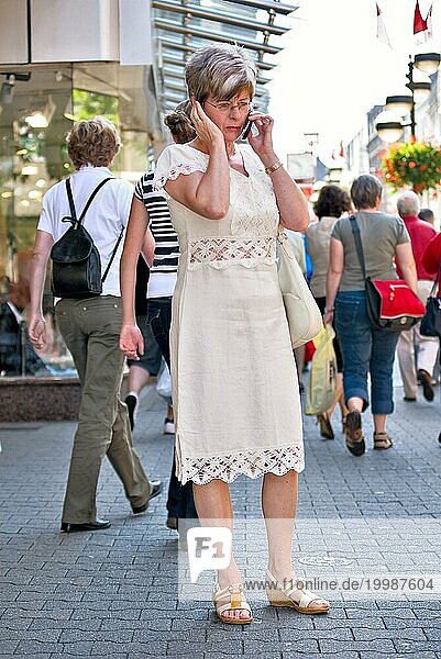 Frau  50 plus  telefoniert auf der Straße mit einem Handy