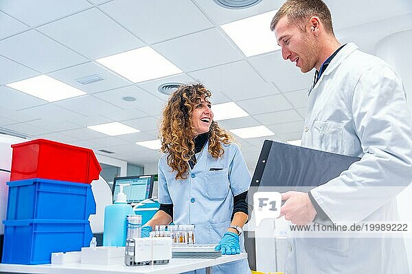 Fröhliche junge Wissenschaftler bei der Arbeit mit Proben in einem pathologischen Forschungslabor in einem Krankenhaus