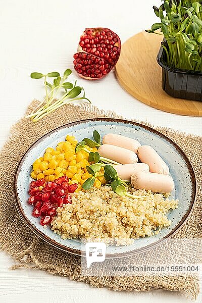 Gemischter Quinoa Brei  süßer Mais  Granatapfelkerne und kleine Würstchen auf weißem Holzhintergrund. Seitenansicht  Nahaufnahme. Essen für Kinder  gesundes Essen Konzept