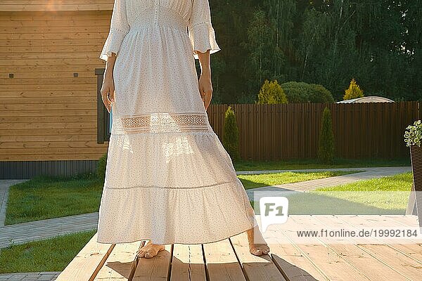 Barfuß Beine einer Frau durch ein dünnes Kleid sichtbar. Unerkennbare Frau auf der Terrasse eines kleinen Hauses