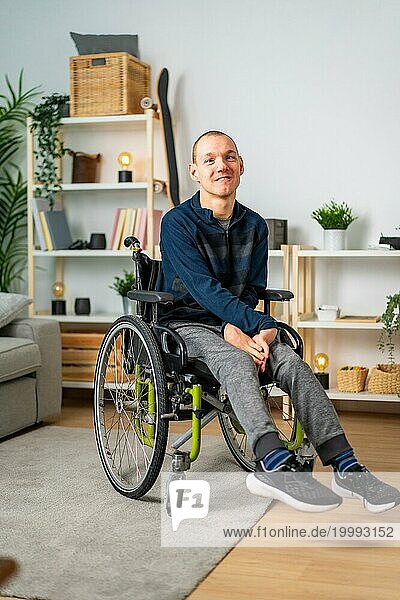 Vertikales Porträt eines glücklichen behinderten Mannes im Rollstuhl zu Hause