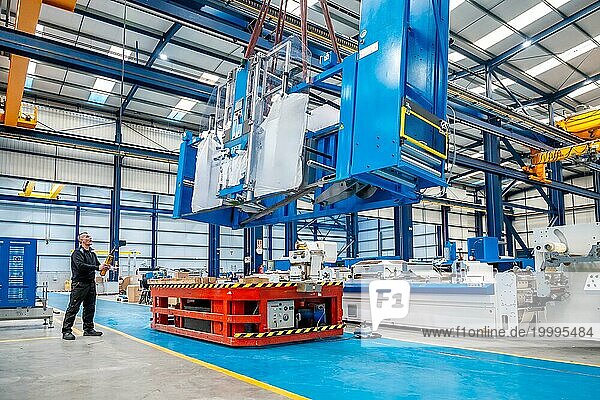 Horizontales Foto mit Kopierbereich eines Krans  der sehr schwere Maschinen in einer Fabrik anhebt