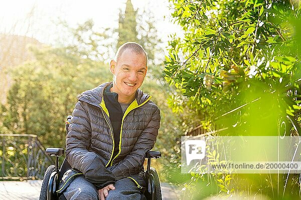 Porträt mit Kopierraum und Fokus auf einen fröhlichen behinderten Mann im Rollstuhl in einem Park