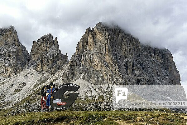 Traditional traditional costume couple advertising sign on the Sella Pass  behind Sassolungo  South Tyrol  Italy  Europe