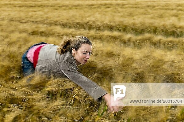 Junge Frau macht Wind im Getreidefeld