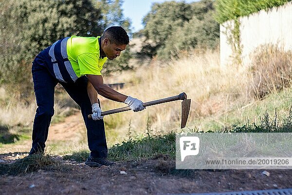 Porträt eines männlichen Latino Gärtners in Arbeitskleidung beim Graben im Boden