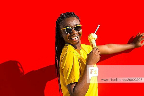 Urbane Szene eines glücklichen Mädchens  das neben einer roten Wand Eiscreme isst